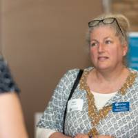Woman wearing GVSU nametag chats with event attendee